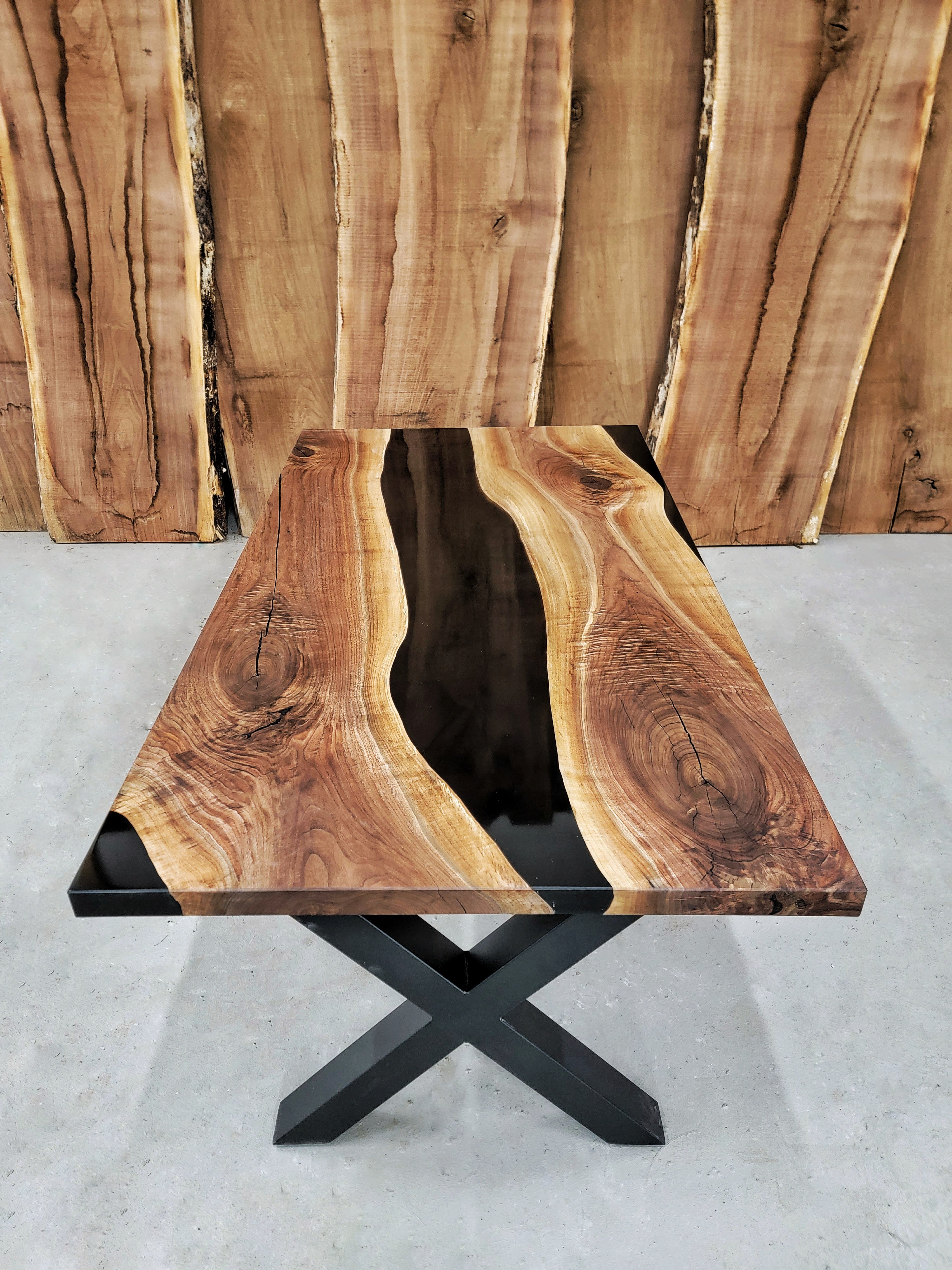 Wooden table with natural grain and black metal base on a gray surface